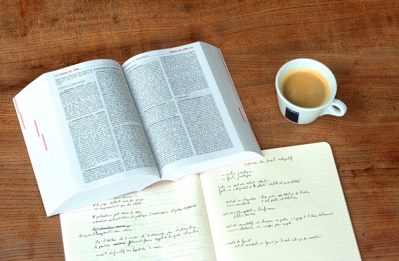 de um livro de leis, um caderno de rascunho e um copo de cafe